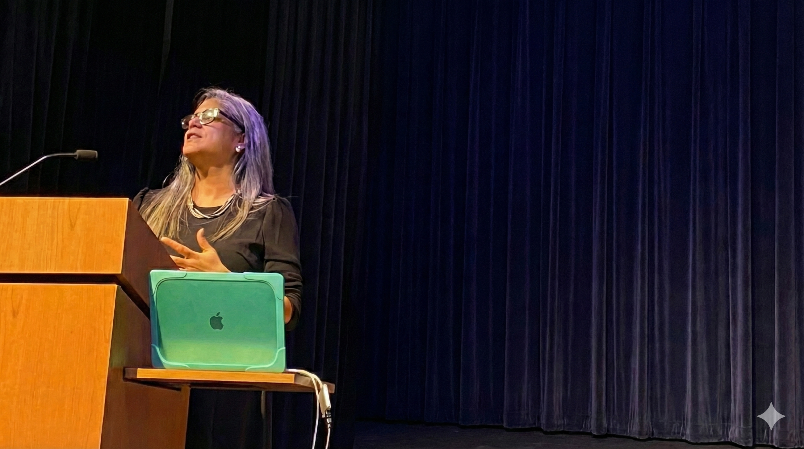 Nicole Greene speaking on stage, addressing an audience